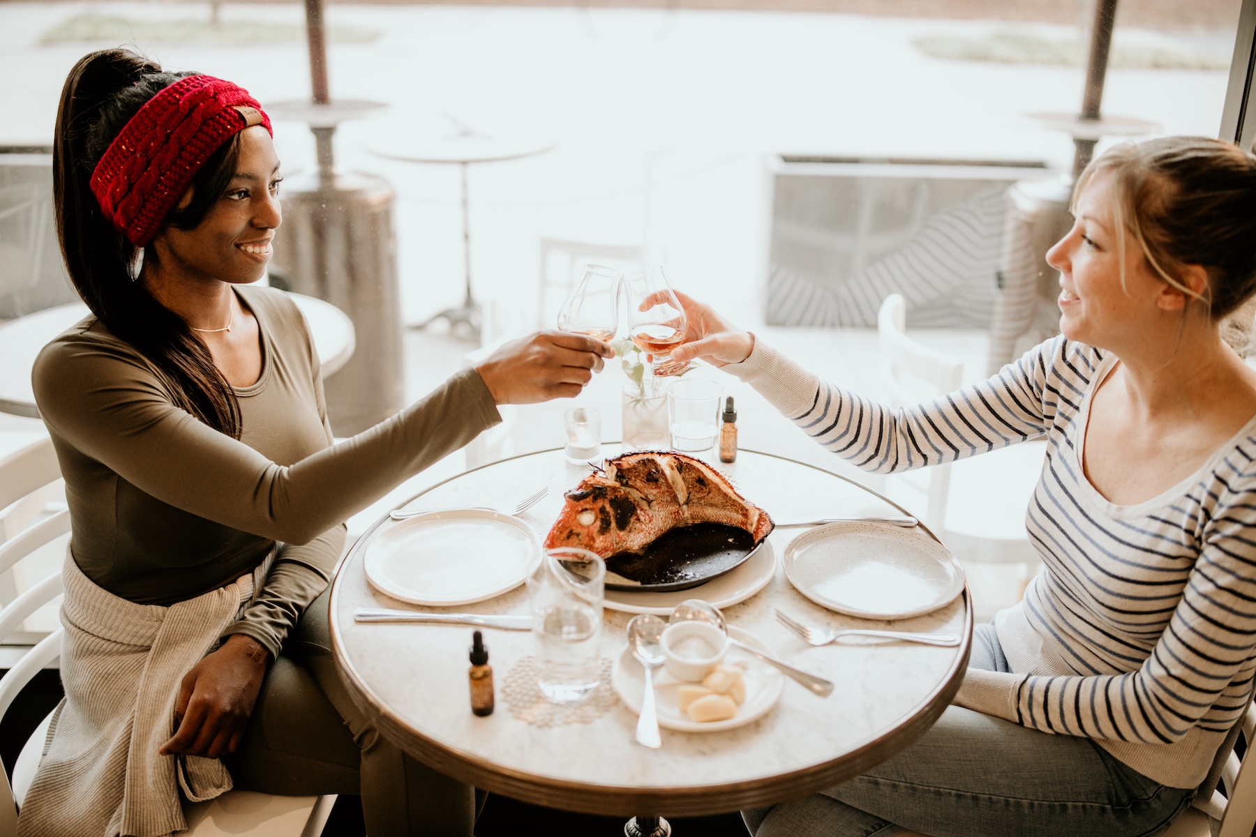 Two women clinking glasses over a shared seafood dish at Easy Bistro, celebrating at an anniversary dinner restaurant near me