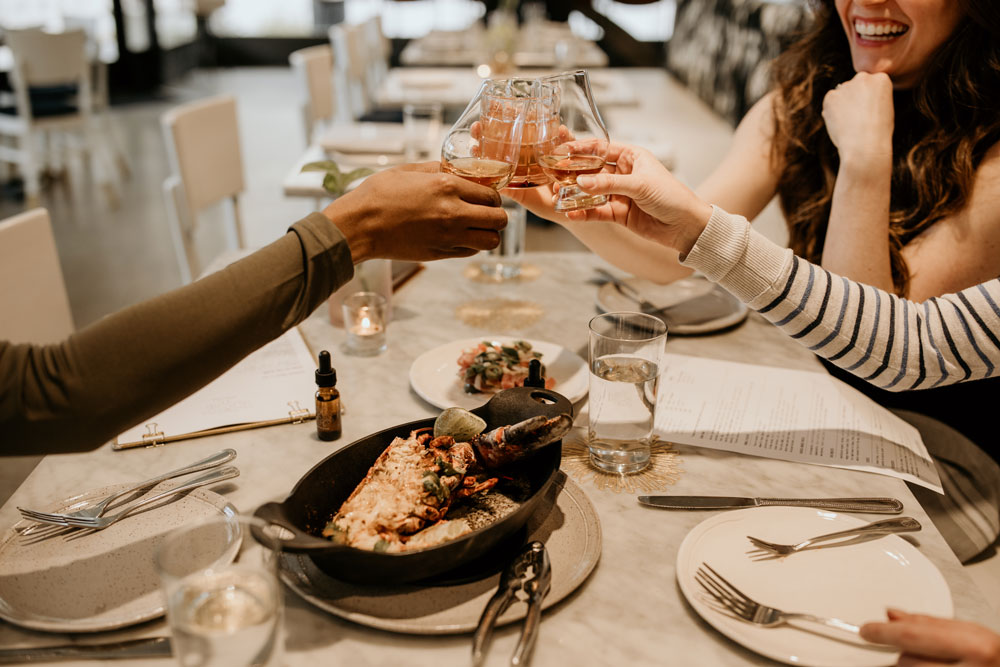An image of three friends clinking their glasses at Easy Bistro, one of the restaurants open on Christmas Eve in Chattanooga.